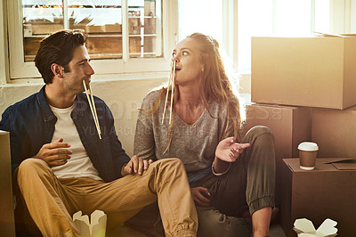 Buy stock photo Shot of a young couple eating takeout while taking a break moving into their new home
