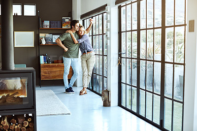 Buy stock photo Shot of a happy young couple standing next to a glass door at home