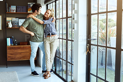Buy stock photo Shot of a happy young couple standing next to a glass door at home