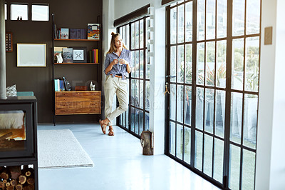 Buy stock photo Full length shot of an attractive young woman enjoying a coffee while standing by a glass door at home