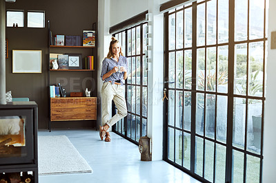 Buy stock photo Full length shot of an attractive young woman enjoying a coffee while standing by a glass door at home