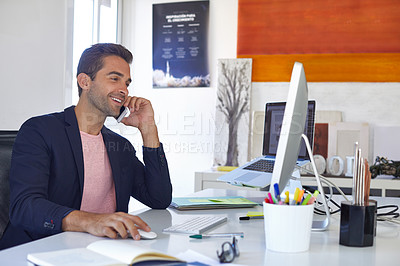Buy stock photo Shot of a young businessman talking on his phone while sitting at his desk