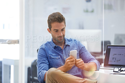Buy stock photo Cropped shot of a young man using his cellphone in his office