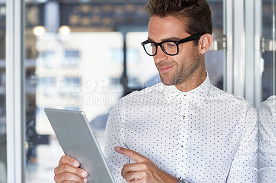 Buy stock photo Cropped shot of a young businessman using his digital tablet in his office