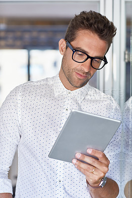 Buy stock photo Cropped shot of a young businessman using his digital tablet in his office