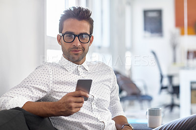Buy stock photo Cropped shot of a young man using his cellphone in his office