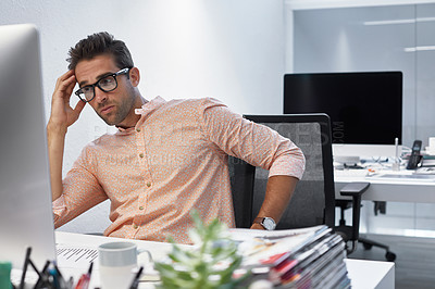 Buy stock photo Shot of a businessman looking exhausted while sitting at his desk