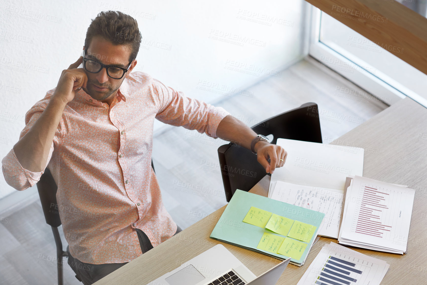Buy stock photo Man, phone call and documents in office for business growth, data analysis and feedback in agency. Above, person and communication in workplace with tech for graphs, stats review or development goals