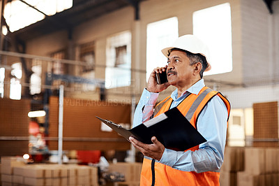 Buy stock photo Shot of a mature man using a smartphone while working in a warehouse