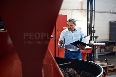 Buy stock photo Shot of a mature man overseeing the production process in a coffee distribution warehouse
