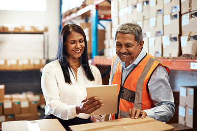 Buy stock photo Shot of a mature man and woman using a digital tablet while working together in a warehouse