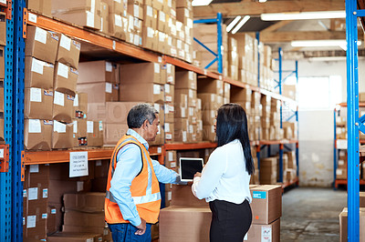 Buy stock photo Shot of a mature man and woman using a digital tablet while working together in a warehouse