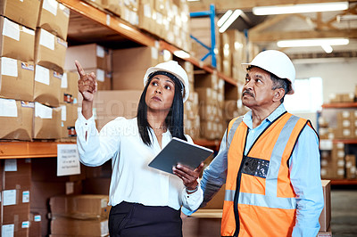 Buy stock photo Shot of a mature man and woman using a digital tablet while working together in a warehouse