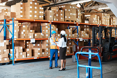 Buy stock photo Shot of a mature man and woman using a digital tablet while working together in a warehouse