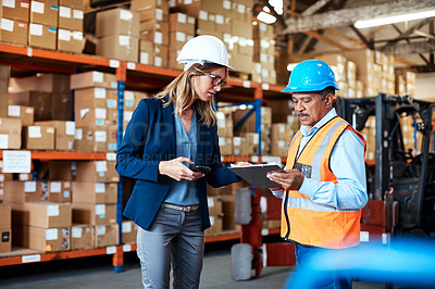 Buy stock photo Shot of a man and woman having a discussion while working together in a warehouse
