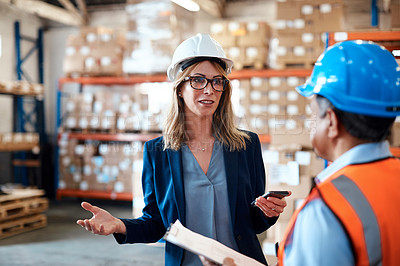 Buy stock photo Shot of a man and woman having a discussion while working together in a warehouse