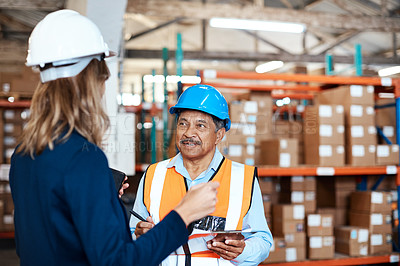 Buy stock photo Shot of a man and woman having a discussion while working together in a warehouse
