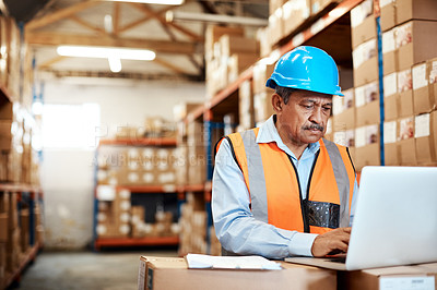 Buy stock photo Shot of a mature man using a laptop while working in a warehouse