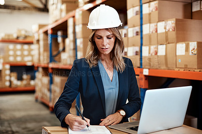 Buy stock photo Shot of a young woman using a laptop while working in a warehouse