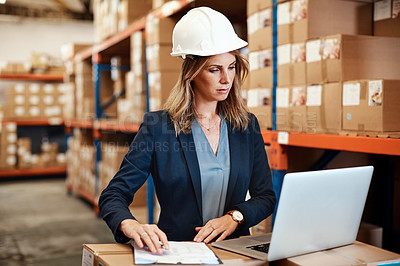 Buy stock photo Shot of a young woman using a laptop while working in a warehouse