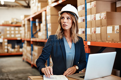 Buy stock photo Shot of a young woman using a laptop while working in a warehouse