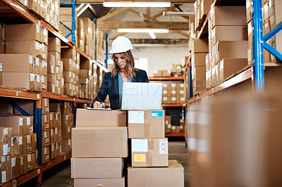 Buy stock photo Shot of a young woman using a laptop while working in a warehouse