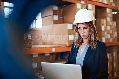 Buy stock photo Shot of a young woman using a laptop while working in a warehouse