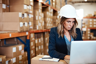 Buy stock photo Shot of a young woman using a laptop while working in a warehouse