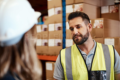 Buy stock photo Shot of a young man and woman having a discussion while working together in a warehouse