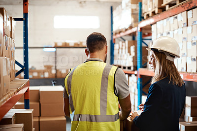 Buy stock photo Shot of a young man and woman having a discussion while working together in a warehouse