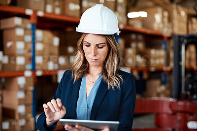 Buy stock photo Shot of a young woman using a digital tablet while working in a warehouse