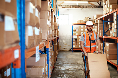 Buy stock photo Shot of a young man moving boxes on a trolley in a warehouse