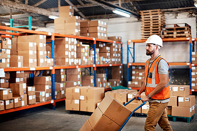 Buy stock photo Shot of a young man moving boxes on a trolley in a warehouse