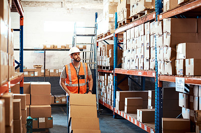Buy stock photo Shot of a young man moving boxes on a trolley in a warehouse