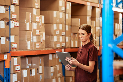 Buy stock photo Shot of a young woman using a digital tablet in a warehouse