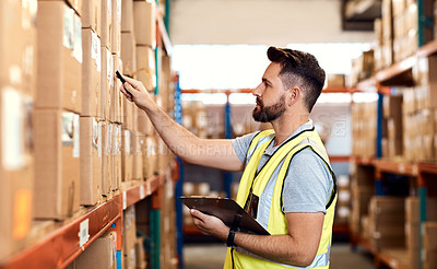 Buy stock photo Shot of a young man using a clipboard while working in a warehouse