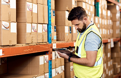 Buy stock photo Shot of a young man using a clipboard while working in a warehouse