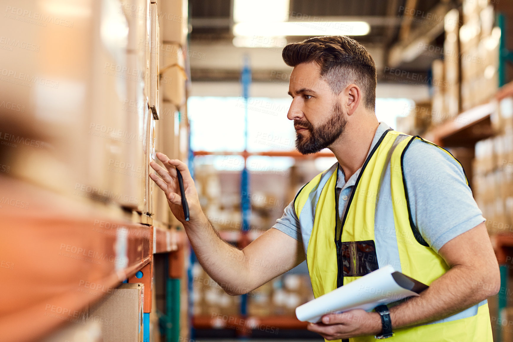 Buy stock photo Shot of a young man using a clipboard while working in a warehouse