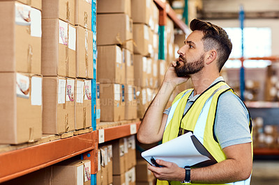Buy stock photo Shot of a young man talking on a cellphone while working in a warehouse