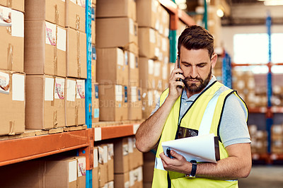 Buy stock photo Shot of a young man talking on a cellphone while working in a warehouse