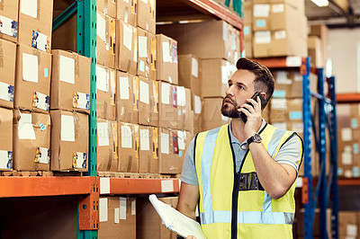 Buy stock photo Shot of a young man talking on a cellphone while working in a warehouse