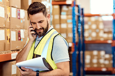 Buy stock photo Shot of a young man talking on a cellphone while working in a warehouse