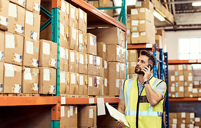 Buy stock photo Shot of a young man talking on a cellphone while working in a warehouse