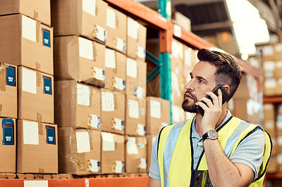 Buy stock photo Shot of a young man talking on a cellphone while working in a warehouse