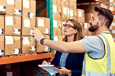 Buy stock photo Shot of a young man and woman working together in a warehouse