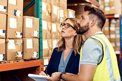 Buy stock photo Shot of a young man and woman working together in a warehouse