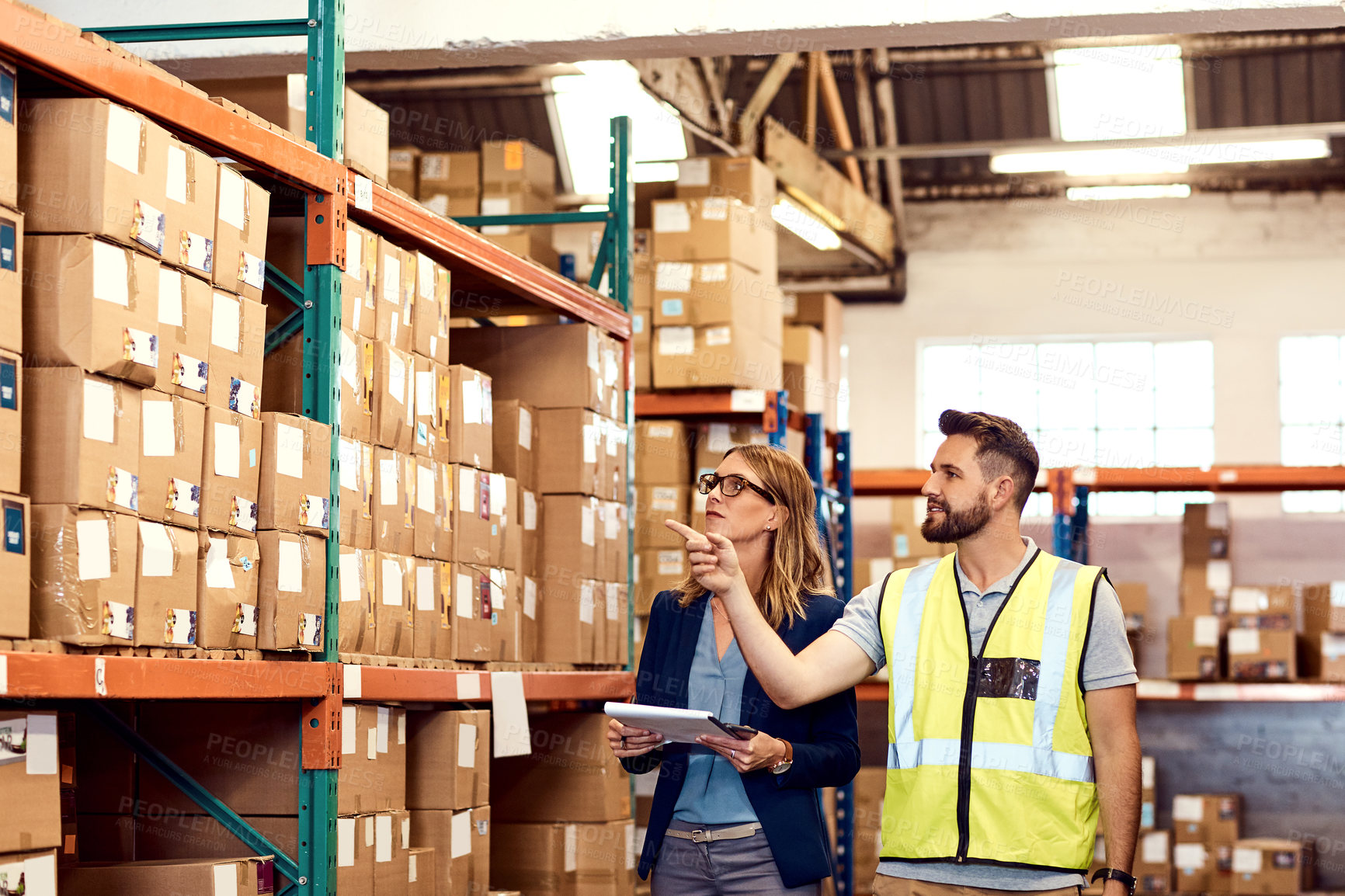 Buy stock photo Shot of a young man and woman working together in a warehouse