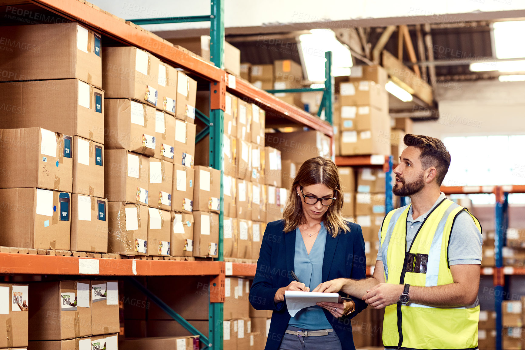 Buy stock photo Shot of a young man and woman working together in a warehouse