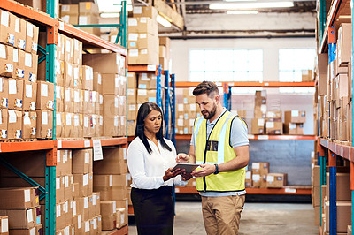 Buy stock photo Shot of a man and a woman using a digital tablet while working together in a warehouse