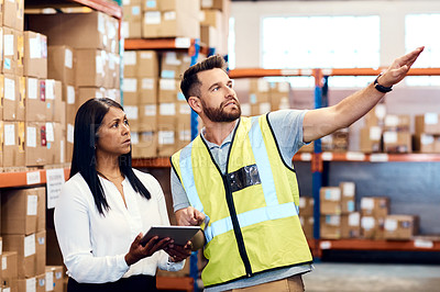 Buy stock photo Shot of a man and a woman using a digital tablet while working together in a warehouse